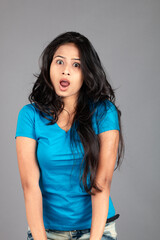 A young woman confidently poses wearing blue t-shirt, distressed denim jeans, heels, showcasing a casual urban style with charm and elegance, suitable for haircare, freedom, self-expression project