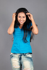 A young woman confidently poses wearing blue t-shirt, distressed denim jeans, heels, showcasing a casual urban style with charm and elegance, suitable for haircare, freedom, self-expression project