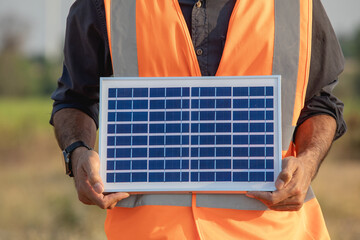 Cropped image of young engineer holding solar panels in wind farm. Clean renewable energy concept