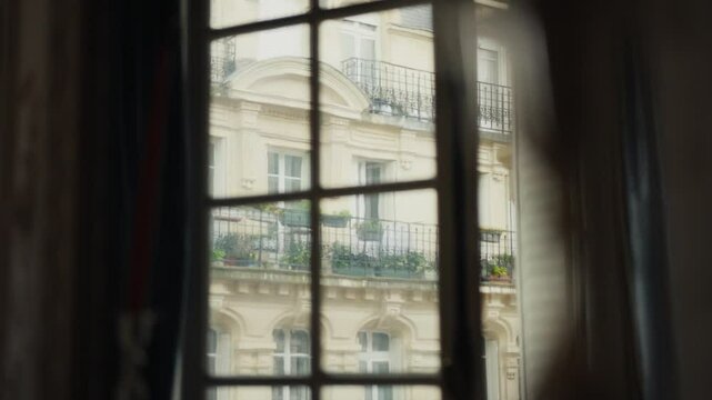 Parisian building seen through window with curtains gently moving