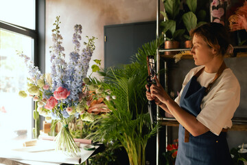 Small flower shop. A woman writes a video blog or online course. Flower school concept. Florist woman creates flower arrangement. . Local business. Part of a series
