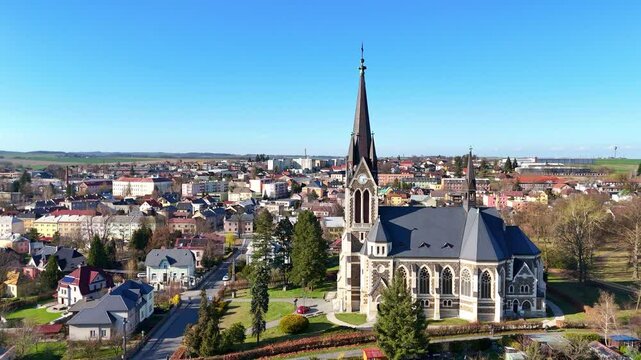 Church spire rises above Vitkov landscape, Czech Republic, surrounded by green spring fields, aerial approach sideview