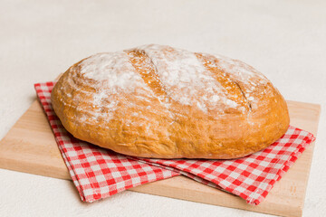 Freshly baked bread on cutting board against white wooden background. perspective view bread with copy space
