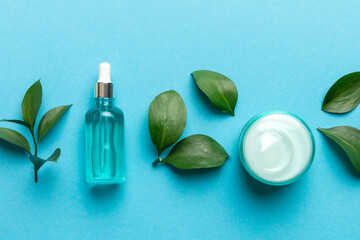Organic cosmetic products with green leaves on color background