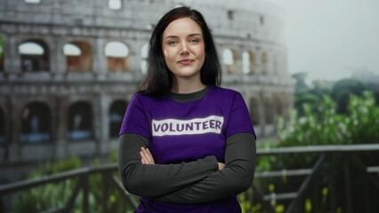Woman with brunette hair and purple volunteer shirt stands confidently with arms crossed in front...