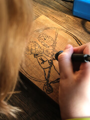Burn out the picture. Woodburning or pyrography. An artist drawing on a wooden plank with...