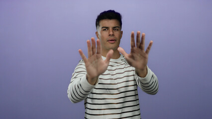 Young man gestures against a purple background, displaying different expressions from clapping to...