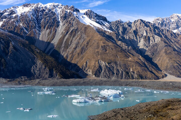 Icebergs floating in glacial lake beneath rugged mountains in Mount Cook National Park, New Zealand