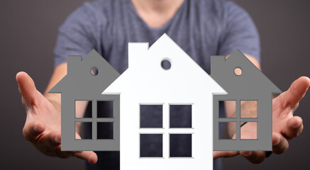 Person presenting three house choices.  Ideal for real estate, home buying, and property investment.