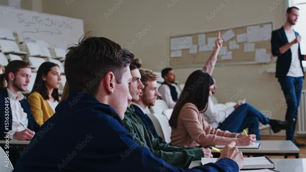 Poster university students are listening attentively to a lecture and taking notes in their notebooks, focu