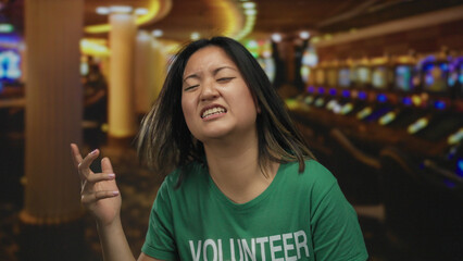 Woman mimicking guitar in casino wearing volunteer t-shirt creates a playful indoor atmosphere with...