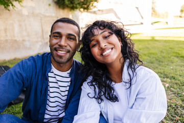 Obraz premium Happy multi ethnic couple smiling outdoors in a park