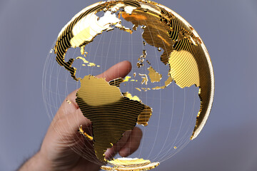 Hand interacting with a golden 3D globe.  Global business, world map, connection, technology...