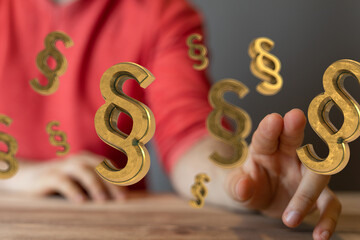 Abstract image of golden paragraph symbols hovering near a person's hand, suggesting legal concepts...