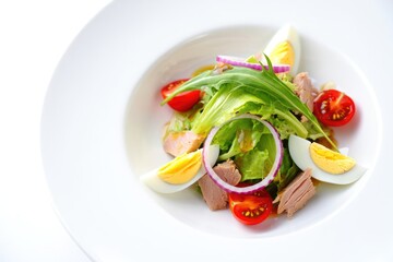 Delicious and healthy tuna salad with tomatoes and eggs served on a white plate, ready to enjoy.