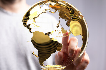 Person touching a digital golden globe, symbolizing global connectivity and networking.