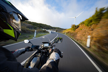 Driver riding motorcycle on empty asphalt road, handlebars view , spring mountains