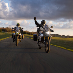 Driver riding motorcycle on empty road during sunset, spring mountains