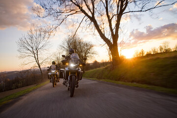 Driver riding motorcycle on empty road during sunset, spring mountains