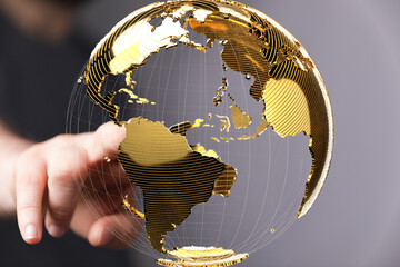 Abstract image of a hand interacting with a golden 3D world globe. Represents global connectivity...