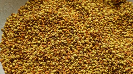Macro image showcasing a close-up of bee pollen granules in various shades of yellow and brown, illustrating the natural texture and detail of this nutrient-rich food product