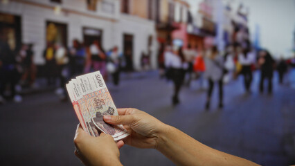 Man holding icelandic krona banknotes on a bustling urban street, capturing the essence of outdoor economic activity and investment in a lively town setting.