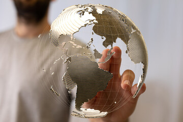 A person's hand interacts with a transparent digital globe, symbolizing global connectivity and...