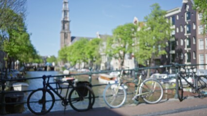 Blurry view of amsterdam canals with defocused bicycles, capturing the essence of dutch urban life under a clear blue sky.