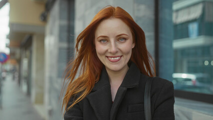 Woman with red hair confidently standing outdoors in city street, showcasing an engaging expression that reflects urban charm.