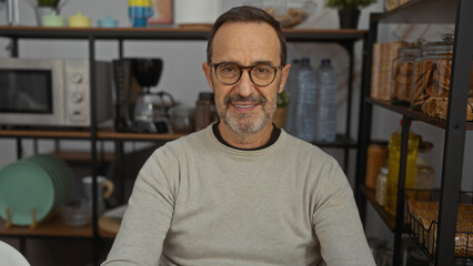 Mature hispanic man smiling in cozy indoor office with shelves and jars in background