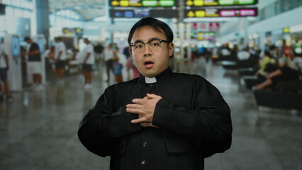 Chinese priest in a bustling airport terminal displaying a worried expression, surrounded by...