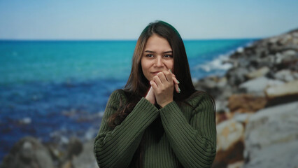Woman standing quietly by the seaside with a pensive expression, the serene ocean backdrop...