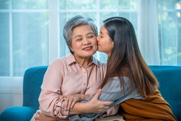 Affectionate granddaughter kissing elderly grandmother at home