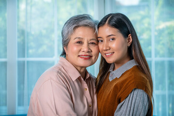Senior grandmother and young granddaughter smiling together at home, looking at camera