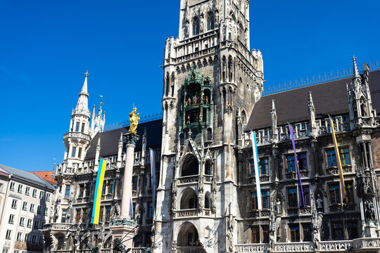 Munich, Bavaria, Germany - April 9 2025: Close-up view of New Town Hall&rsquo;s ornate tower and Glockenspiel at Marienplatz with golden Mariens&auml;ule under a clear spring sky.