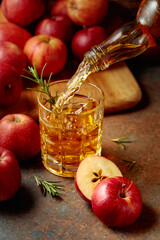 Apple cider is poured from a bottle into a glass.