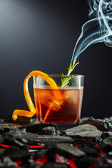 Old-fashioned cocktail  with a burning twig of rosemary.