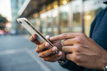 Close up of male hands using a smartphone outdoors in the city
