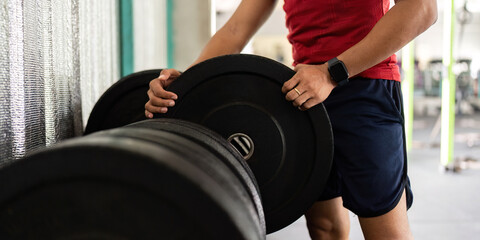 Weightlifting and Fitness. Man adjusting weights in the gym, focusing on strength training.