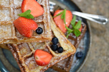 Delicious cake served with fresh strawberries and blueberries alongside crispy waffles.