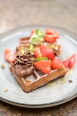 Bright and airy breakfast scene featuring waffles topped with fresh strawberries, blueberries, and mint leaves, beautifully plated.