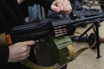The man confidently holds a machine gun with ammunition in his hands. A military, tactical, or combat concept with an emphasis on weapons and readiness