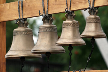 Four small bells hanging on ropes, gently swaying in the breeze. A minimalist and peaceful scene evoking tranquility, simplicity, and rustic charm