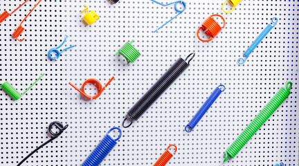 Colorful assortment of metal springs on perforated background