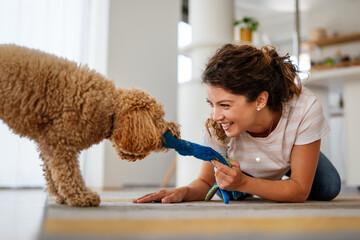 Young happy owner woman with her best friend dog playing and spending quality time together at home