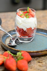 Close-up of Strawberries Romanoff dessert in a glass – layered fresh strawberries, whipped cream, and mint.