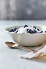 Healthy breakfast bowl with yogurt, blueberries and granola on a bright background. Copy space.