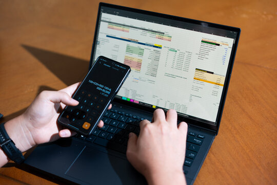 A person is using a calculator and laptop at the same time