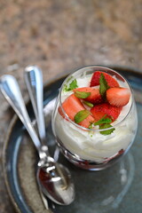 Close-up of Strawberries Romanoff dessert in a glass – layered fresh strawberries, whipped cream, and mint.