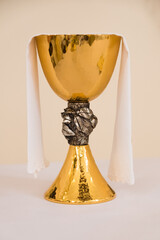 Golden Chalice - Symbol of Faith and Tradition. A gleaming, ornate chalice draped with a white cloth, set against a soft, muted background, often used in religious ceremonies